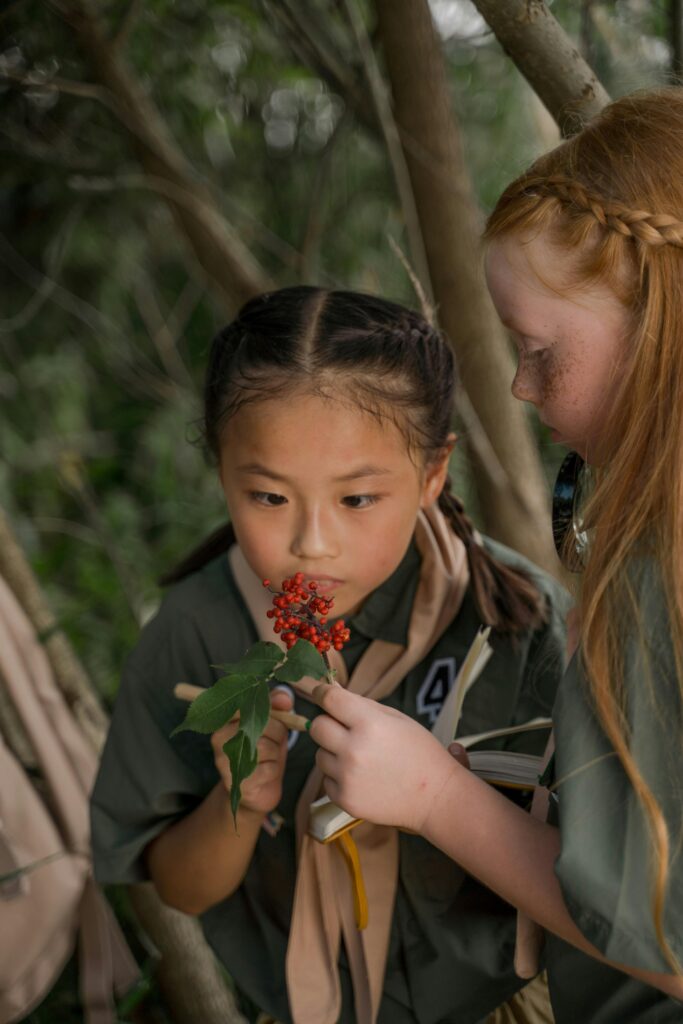 two girls studying a plant with a magnifying glass