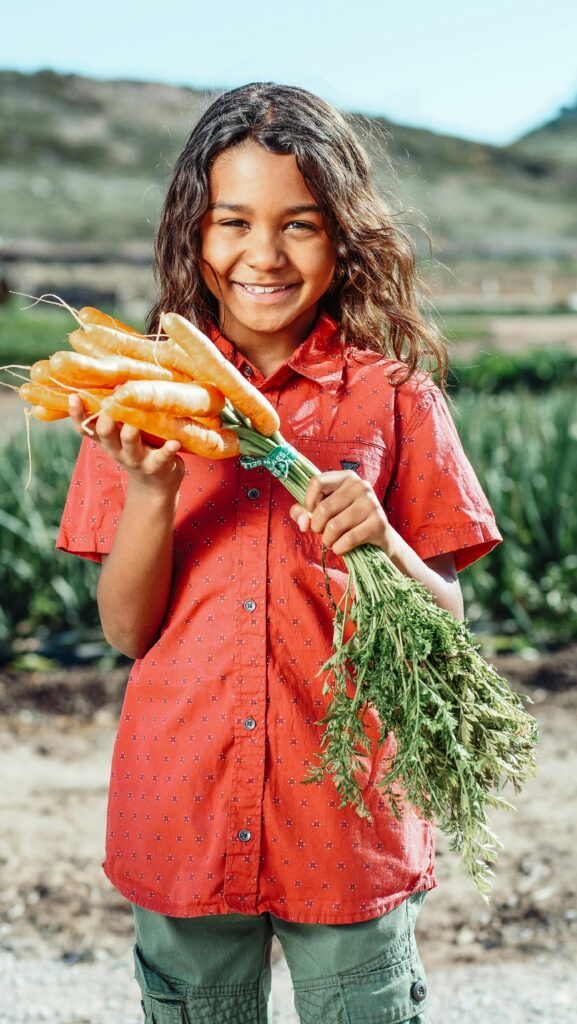 boy holding a bunch of fresh carrots in the garden
