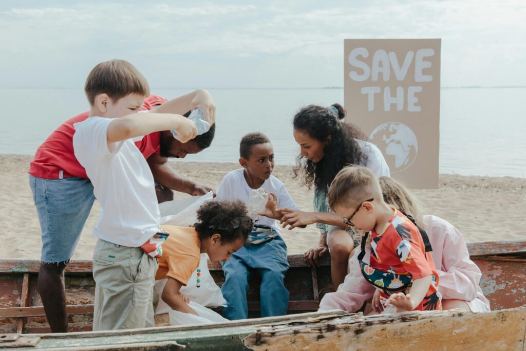 woman showing kids and toddlers how to celebrate earth day ash the beach with a save the earth sign in the background