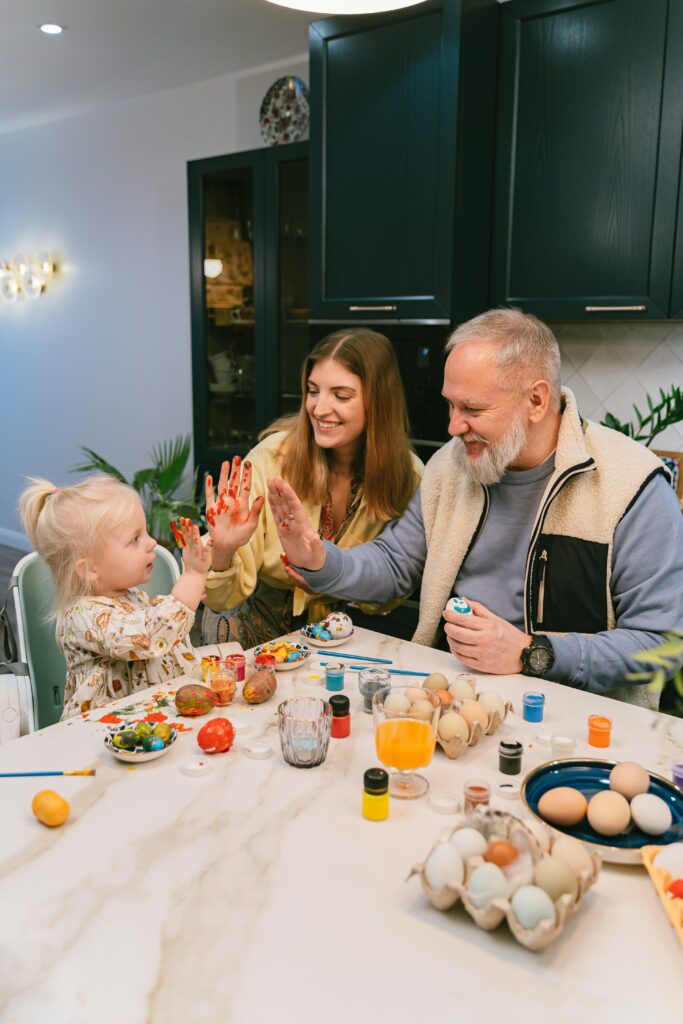 child, mother and grandfather painting easter eggs