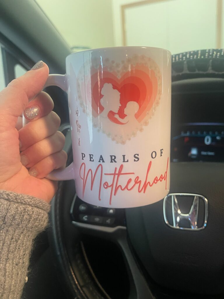 hand holding a Pearls of Motherhood mug filled with coffee