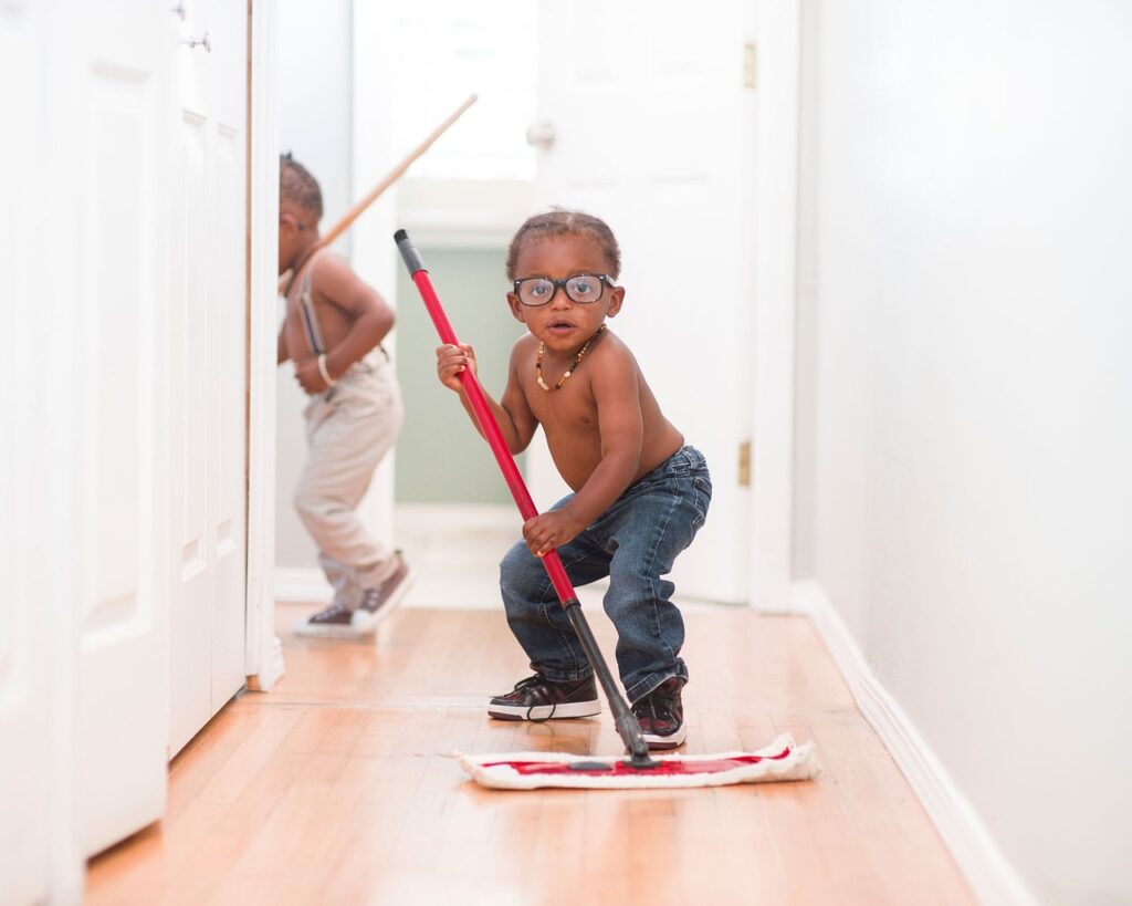 little boy in glasses holding a mop to help clean