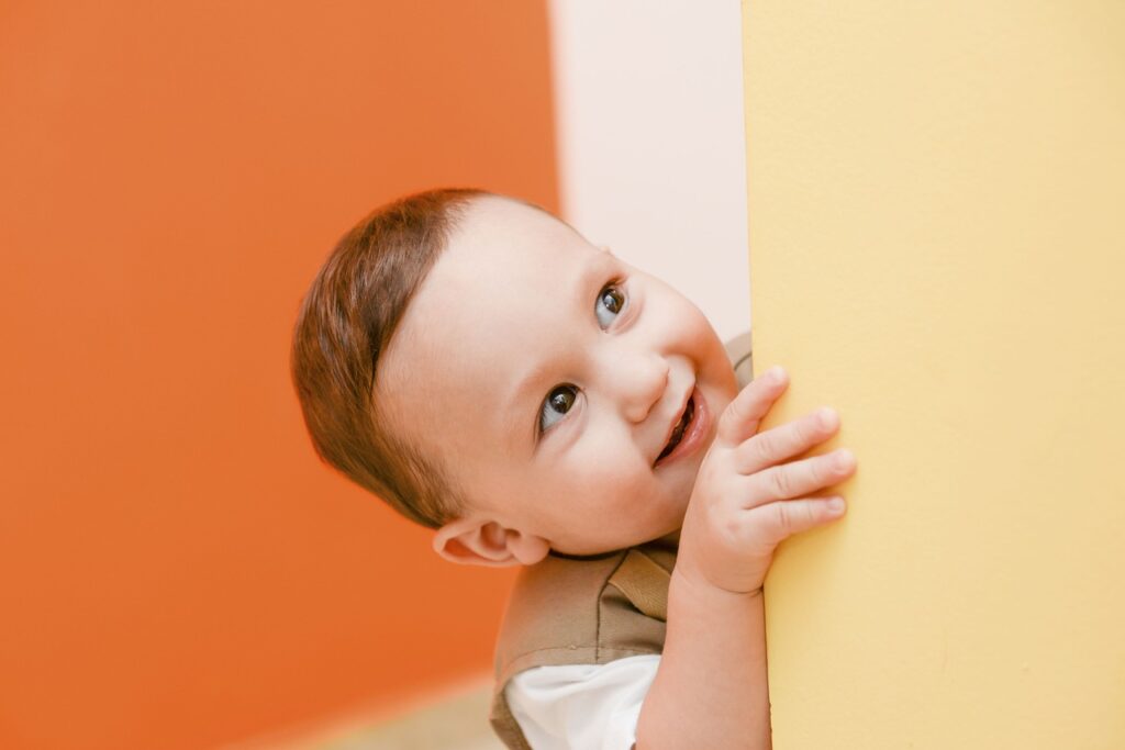 child mischievously peering around corner
