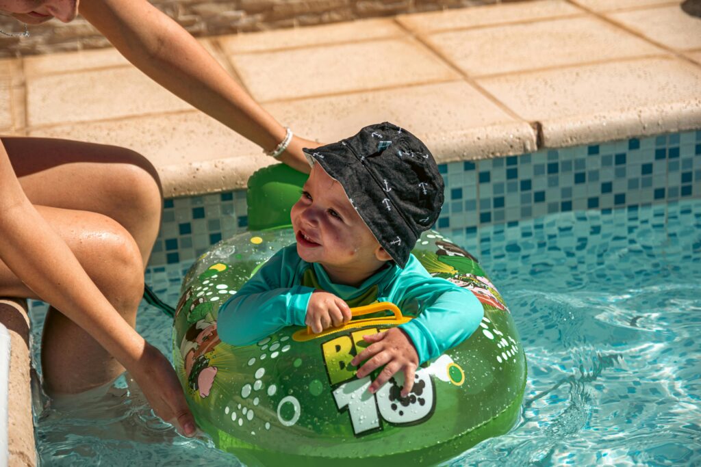 child in pool with sun hat and rash guard