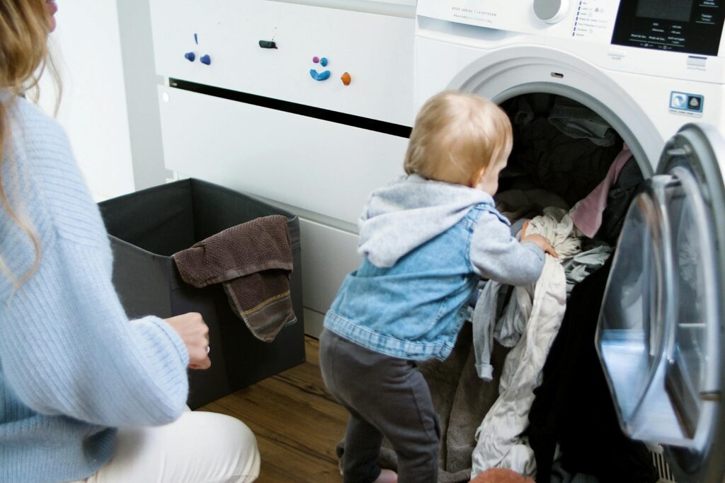 child helping mom clean by taking out the laundry