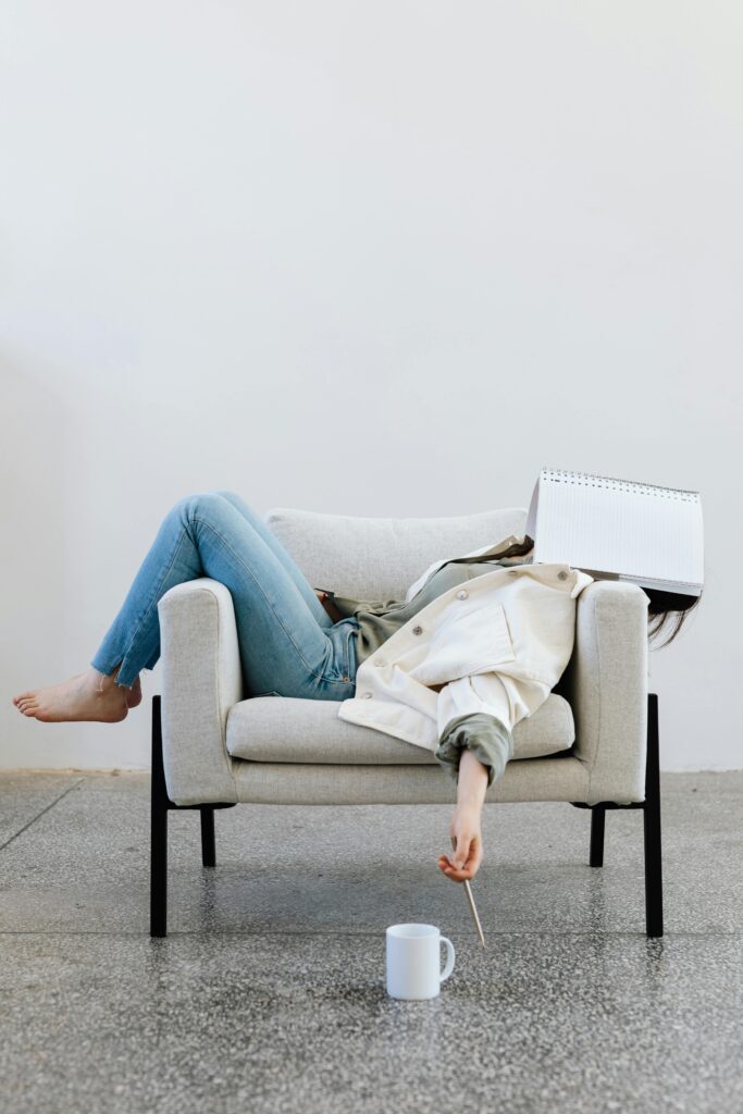 woman burns out reclined in a chair with notebook over her face in defeat