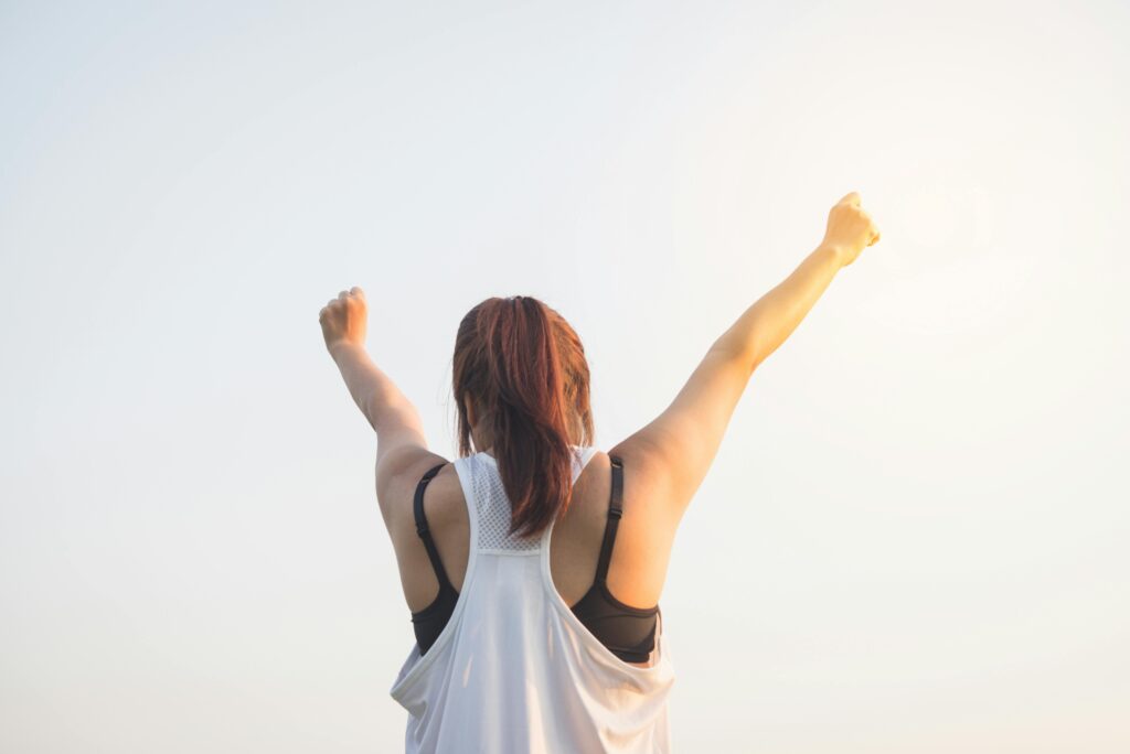 woman raising arms in victory in a sunrise 