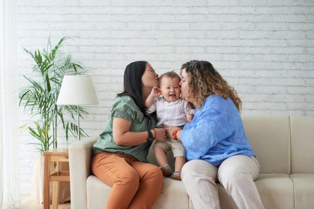 two women kissing a baby's head