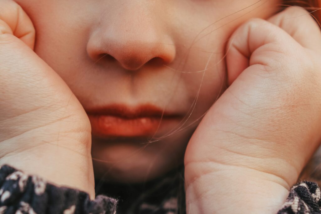 close up of child's nose and mouth with their hands on cheeks